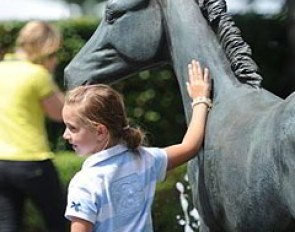 A young horse fan posing with one of the bronze sculptures