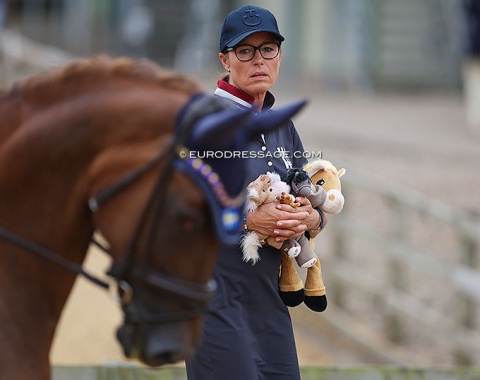 Emma Kaberg's mom holding lucky horse mascots as her daughter enters the arena