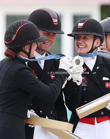 The Danish silver medalists do "cheers" with their medals on the podium