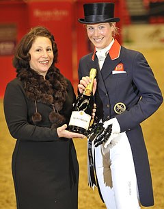 Lisa Wells, representative for Reem Acra, presents Laura Bechtolsheimer with her winner's rosette and a bottle of champagne